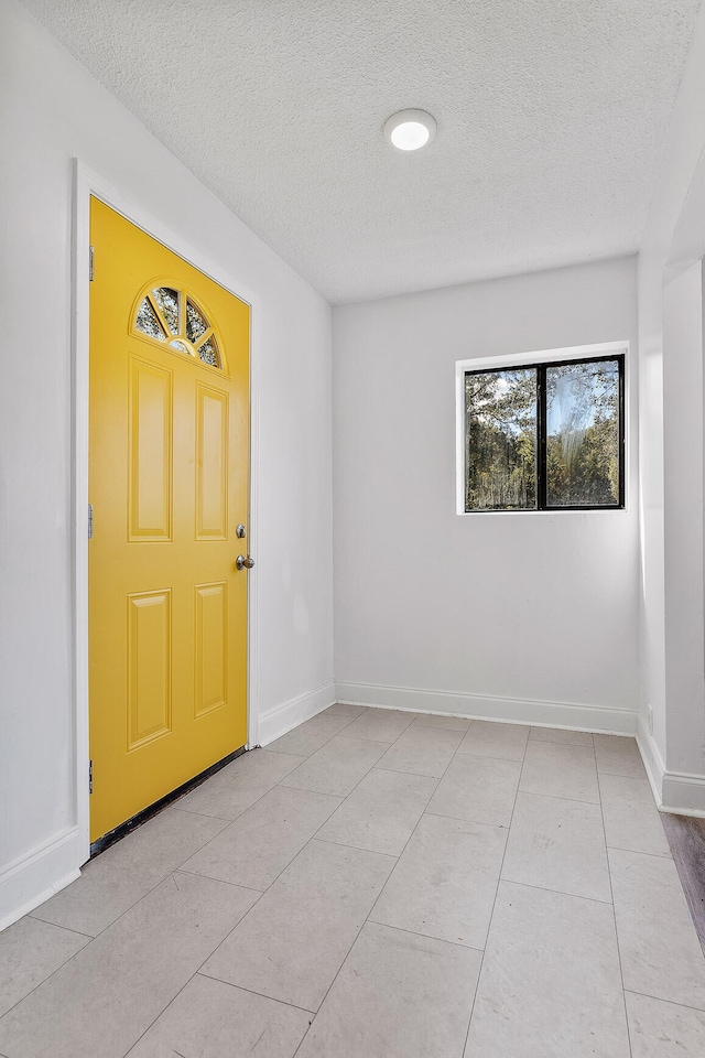 tiled empty room featuring a textured ceiling