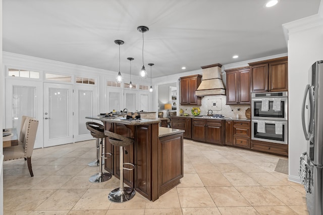 kitchen with a kitchen island, stainless steel appliances, pendant lighting, a breakfast bar, and premium range hood