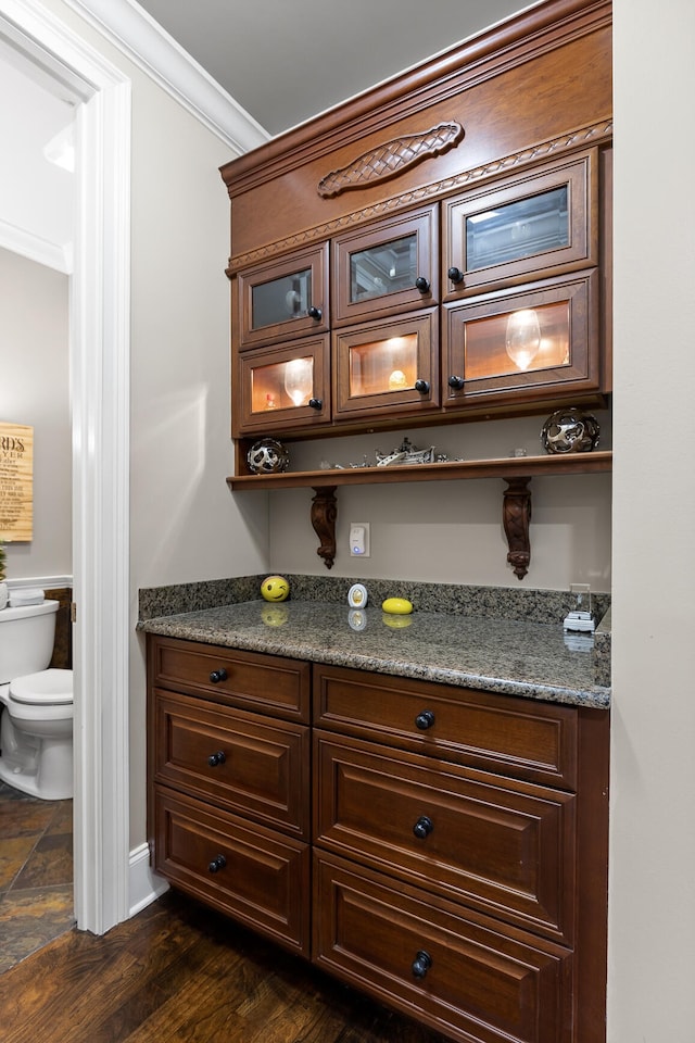 bar featuring ornamental molding, dark stone countertops, and dark hardwood / wood-style flooring