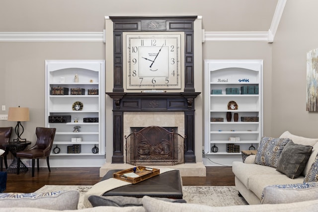 living room with built in shelves, ornamental molding, a tile fireplace, and dark hardwood / wood-style flooring