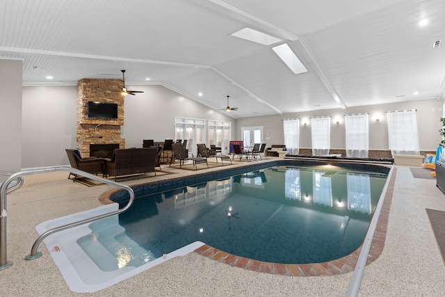 view of swimming pool featuring a stone fireplace and a skylight