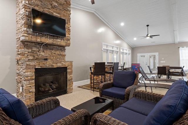 living room with ceiling fan, high vaulted ceiling, ornamental molding, a stone fireplace, and french doors