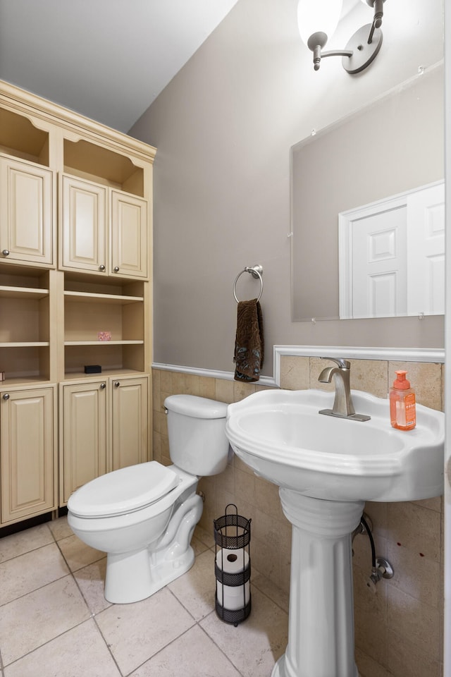 bathroom with toilet, tile walls, and tile patterned flooring