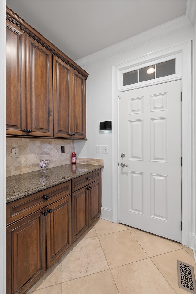 clothes washing area featuring crown molding and light tile patterned floors