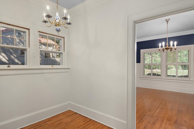 unfurnished dining area featuring ornamental molding, hardwood / wood-style flooring, and a chandelier