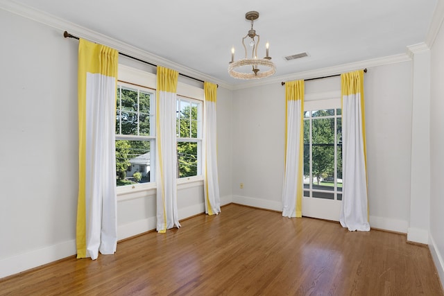 unfurnished room with crown molding, hardwood / wood-style floors, a notable chandelier, and a wealth of natural light