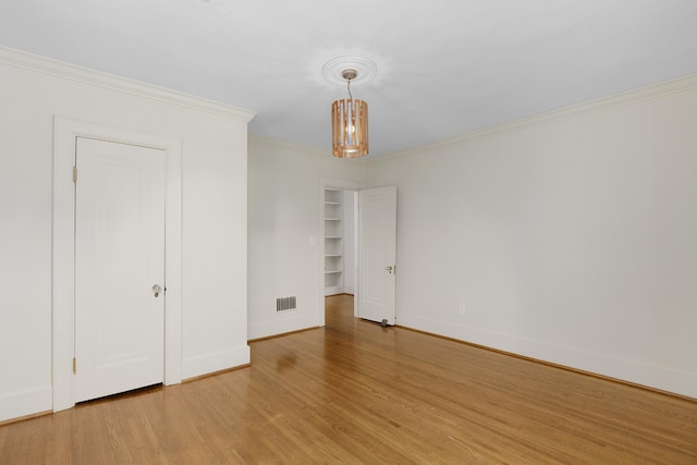 empty room featuring ornamental molding, light hardwood / wood-style flooring, and an inviting chandelier