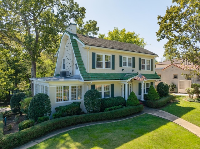 colonial-style house featuring cooling unit and a front yard