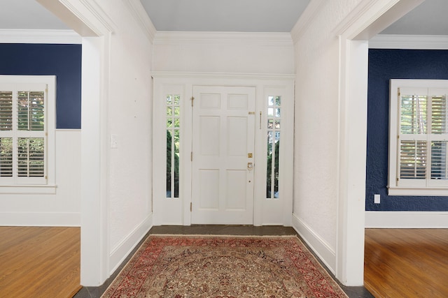 foyer with dark wood-type flooring, a healthy amount of sunlight, and ornamental molding