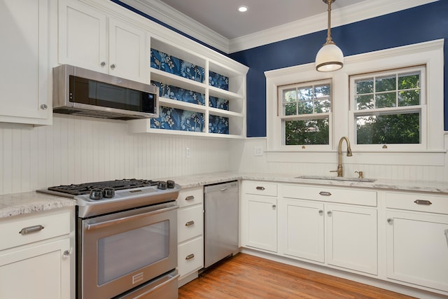 kitchen featuring white cabinets, hanging light fixtures, light wood-type flooring, sink, and stainless steel appliances