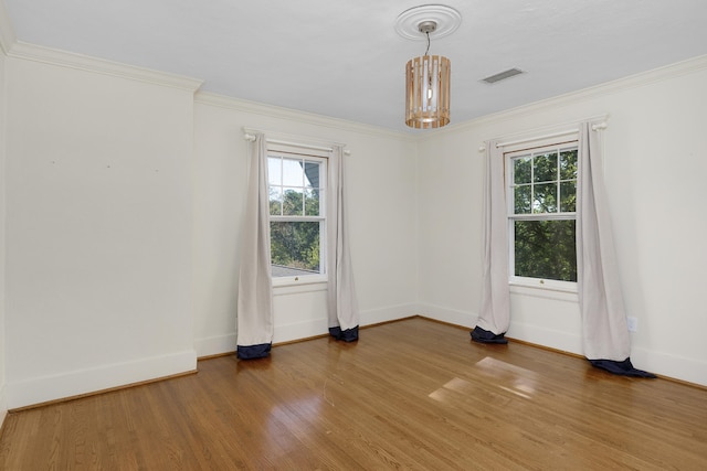 empty room with hardwood / wood-style flooring, ornamental molding, and a chandelier