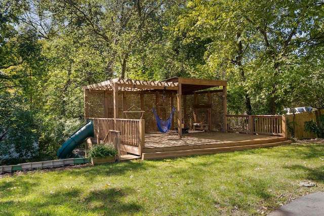 view of play area featuring a wooden deck, a lawn, and a pergola