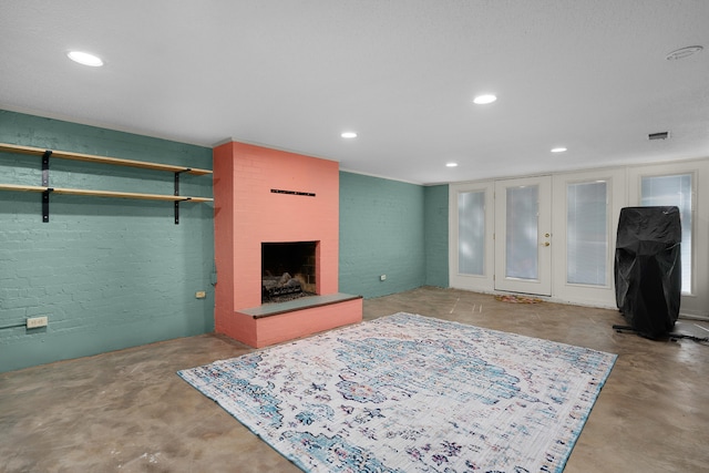 living room with french doors, concrete flooring, and a fireplace