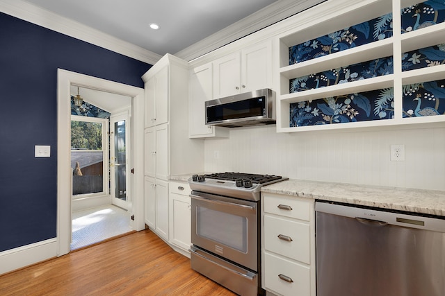 kitchen featuring light stone countertops, appliances with stainless steel finishes, light hardwood / wood-style floors, white cabinets, and crown molding