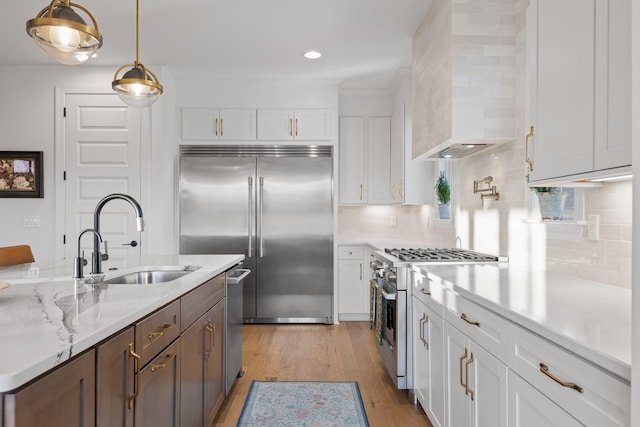 kitchen with white cabinetry, sink, high quality appliances, pendant lighting, and decorative backsplash