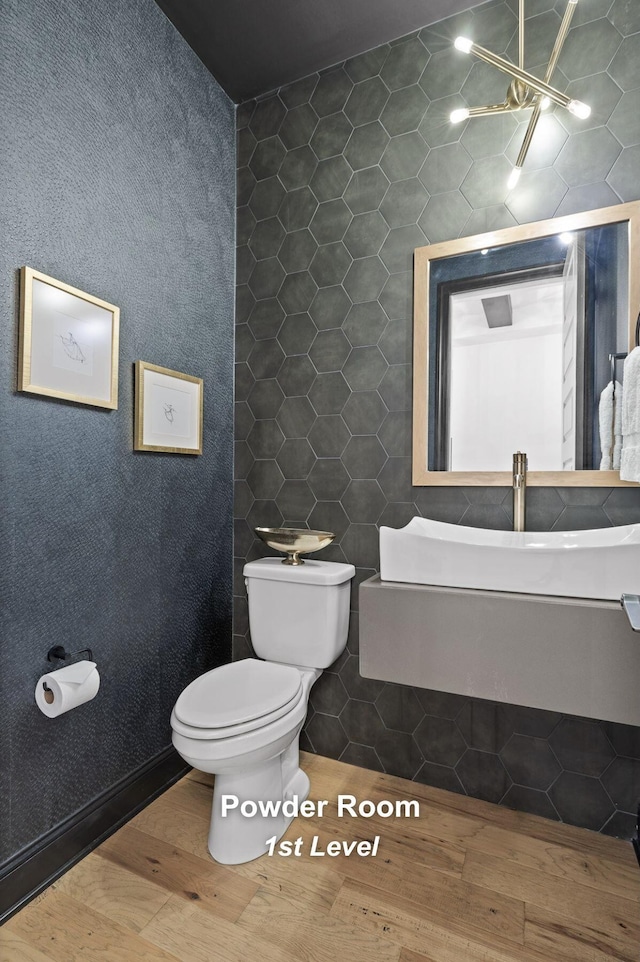 bathroom featuring wood-type flooring, toilet, and tile walls