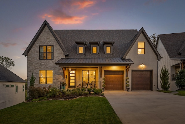 view of front of property with a porch, a garage, and a lawn