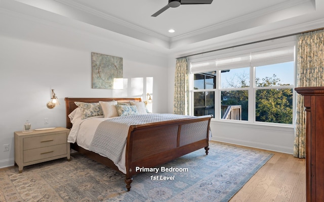 bedroom featuring a tray ceiling, ceiling fan, wood-type flooring, and ornamental molding