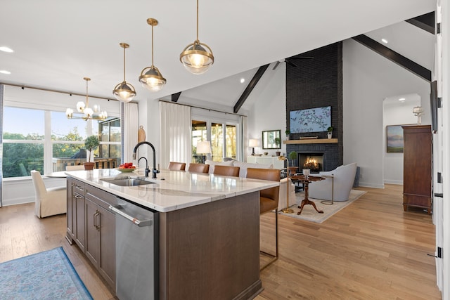 kitchen featuring light stone countertops, dishwasher, sink, a brick fireplace, and vaulted ceiling with beams