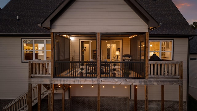 back house at dusk featuring a balcony