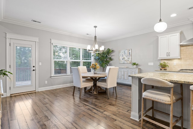 dining space featuring crown molding, a notable chandelier, and dark hardwood / wood-style flooring