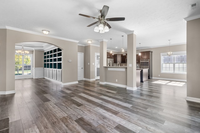 unfurnished living room featuring crown molding, dark hardwood / wood-style floors, ceiling fan with notable chandelier, and a wealth of natural light