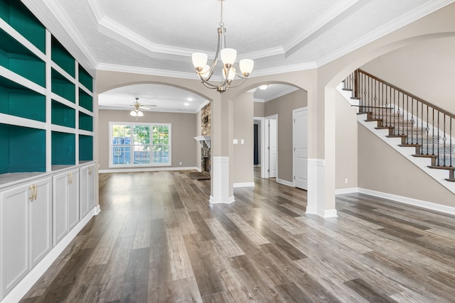 unfurnished dining area with a raised ceiling, ornamental molding, a stone fireplace, and hardwood / wood-style floors