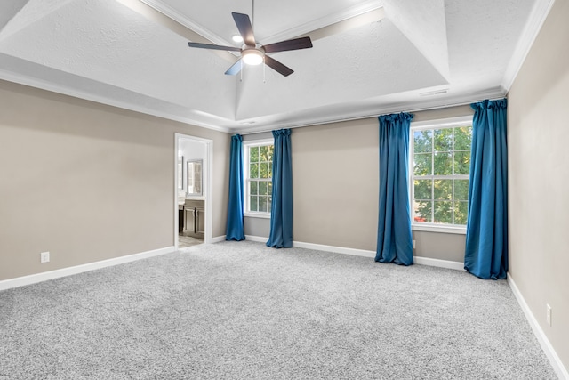 unfurnished room featuring a raised ceiling, a textured ceiling, ceiling fan, crown molding, and light colored carpet