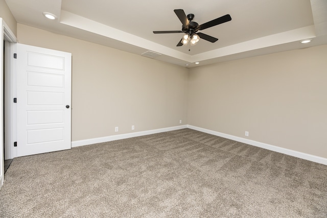 spare room featuring carpet, a tray ceiling, and ceiling fan