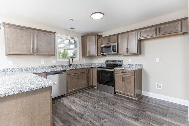 kitchen featuring pendant lighting, light stone countertops, stainless steel appliances, and dark hardwood / wood-style flooring