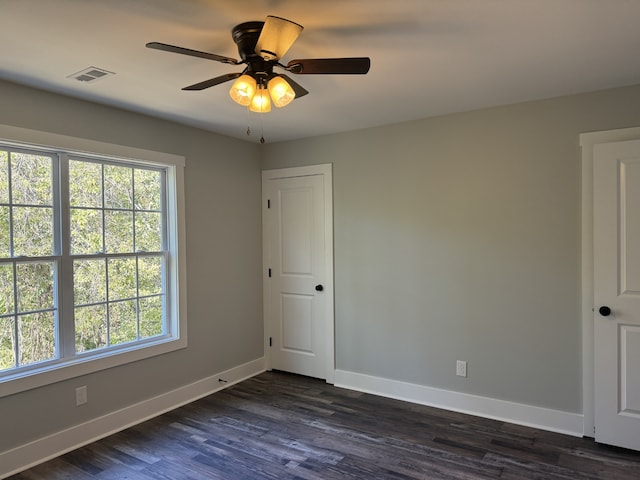 empty room with ceiling fan and dark hardwood / wood-style flooring