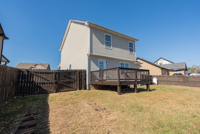 rear view of house featuring a wooden deck and a lawn