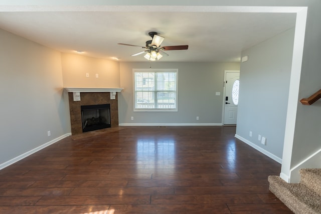 unfurnished living room featuring dark hardwood / wood-style floors, a tile fireplace, and ceiling fan