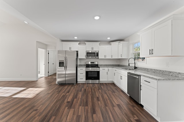 kitchen with stainless steel appliances, sink, light stone countertops, white cabinetry, and dark hardwood / wood-style flooring