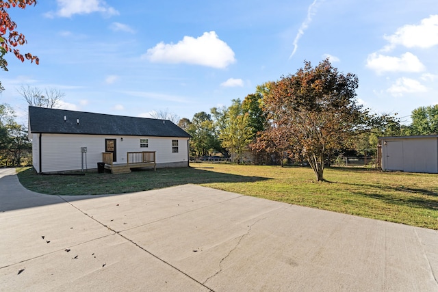 back of property with a yard, a patio area, and a storage shed