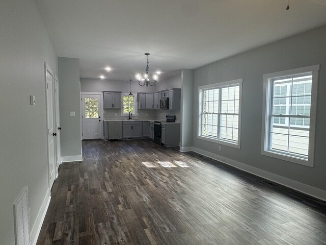 954 Greenwood Ave, Clarksville, TN 37040 - unfurnished living room featuring a notable chandelier, plenty of natural light, baseboards, dark wood-type flooring, and visible vents