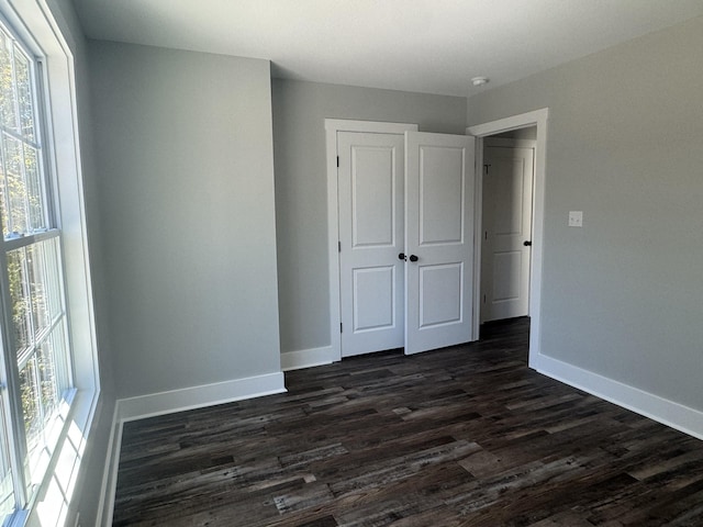 954 Greenwood Ave, Clarksville, TN 37040 - unfurnished bedroom with baseboards, dark wood finished floors, multiple windows, and a closet
