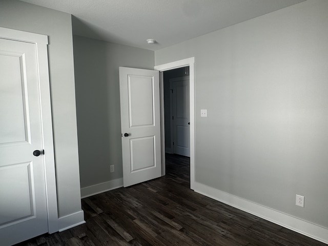 unfurnished bedroom with dark hardwood / wood-style flooring