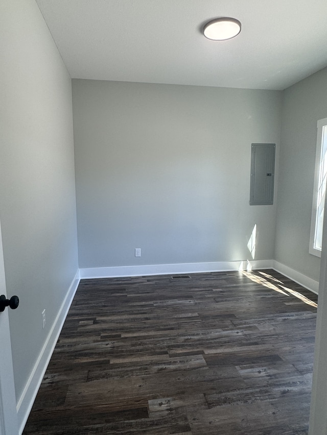 unfurnished room featuring electric panel and dark wood-type flooring