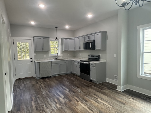 kitchen featuring gray cabinetry, stainless steel appliances, dark hardwood / wood-style floors, and hanging light fixtures