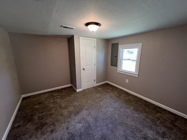 unfurnished bedroom featuring a textured ceiling, electric panel, and dark carpet