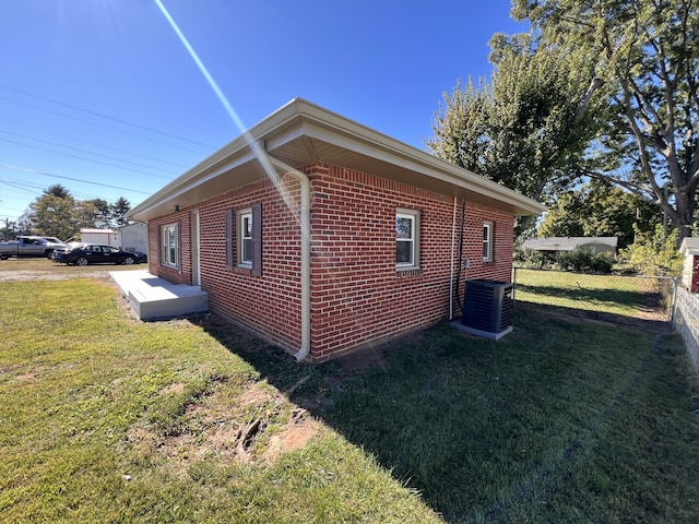 view of side of home featuring a yard and central AC unit