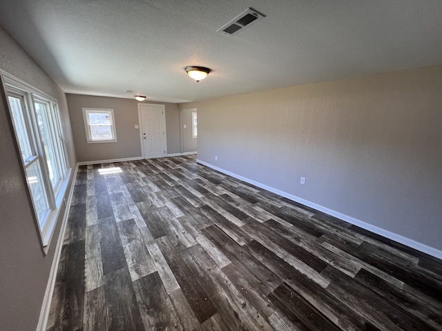 empty room with a textured ceiling and dark hardwood / wood-style floors