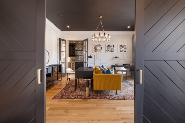 dining space featuring an inviting chandelier, wooden walls, and light wood-type flooring