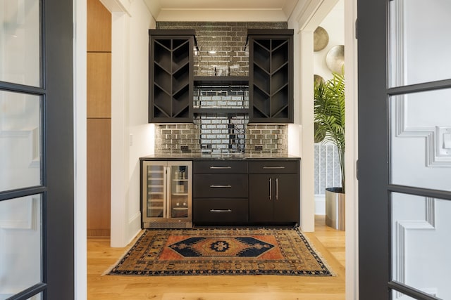 bar featuring wine cooler, decorative backsplash, and hardwood / wood-style flooring