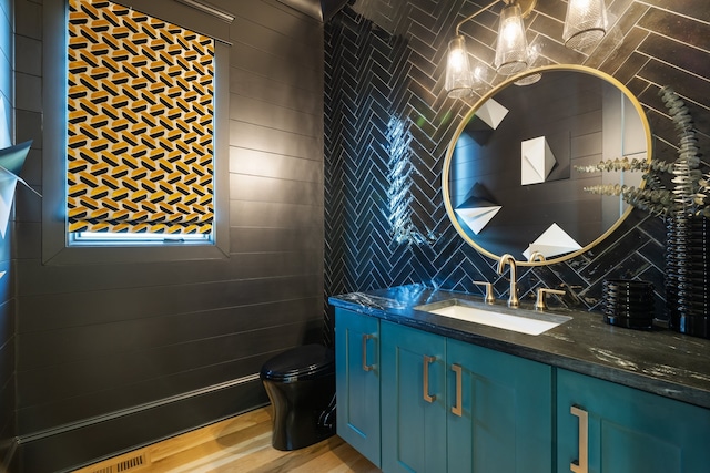 bathroom with vanity, toilet, and tile walls