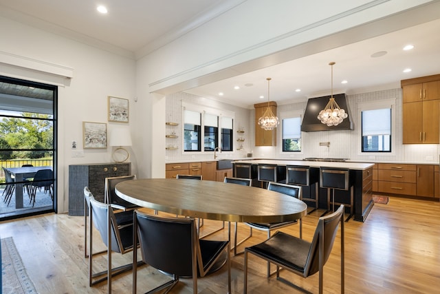 dining area featuring a wealth of natural light, an inviting chandelier, crown molding, and light hardwood / wood-style floors