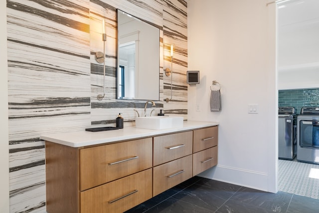 bathroom with vanity, washer and clothes dryer, and backsplash