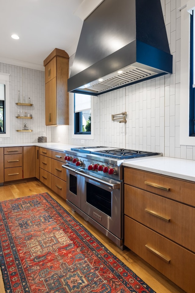 kitchen featuring dark hardwood / wood-style floors, wall chimney exhaust hood, range with two ovens, backsplash, and ornamental molding