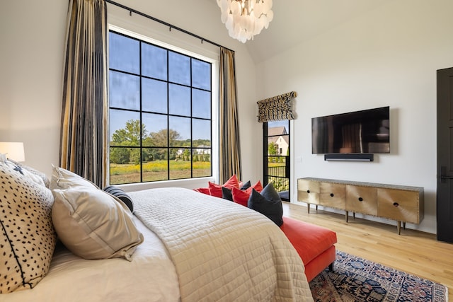 bedroom with vaulted ceiling, wood-type flooring, multiple windows, and an inviting chandelier